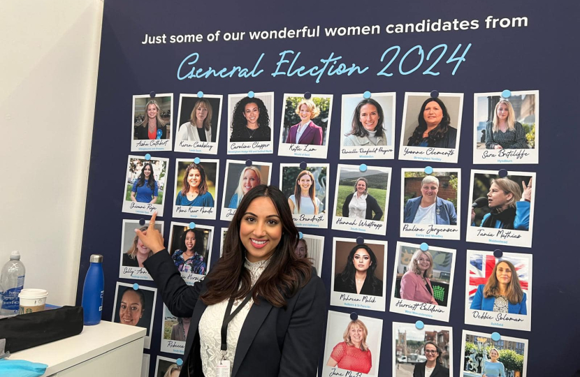 Shivani Raja MP stood next to a photograph of herself on a board of new female Conservative MP's